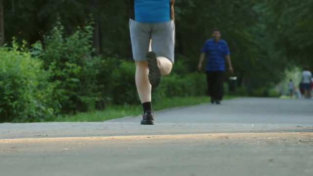 Young man runs in a park - feet level