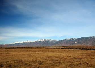 blue sky over the vast steppes, Tunka valley, mountains covered with snow, Sayan mountains. Used deep toning of the photo 
