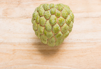 Green custard apple on the wooden floor.