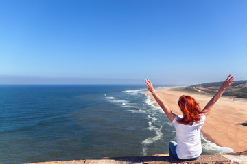 Woman smiling arms raised up to blue sky, celebrating freedom. Positive human emotions, life success, peace of mind concept. Free Happy girl on beach enjoying nature