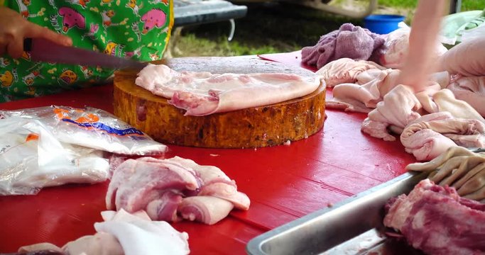 Close up of a woman cutting the skin off a pig in local market, Thailand 
