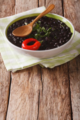 stewed black beans with spices and herbs in a bowl close-up. vertical
