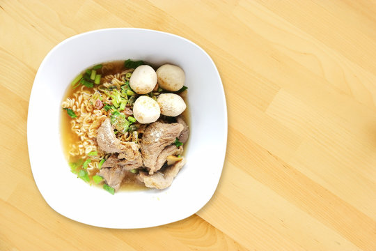 Top View Spicy Rich Flavour Noodle With Sliced Pork and Pork Balls, Street Food Style On Wooden Background