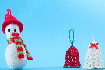 Knitted snowman on a blue background with bells. Christmas cards.
