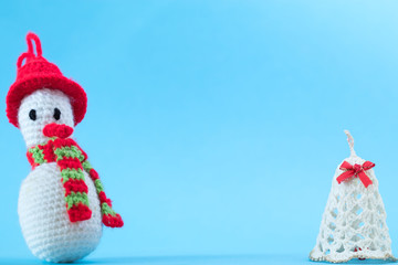 Knitted snowman on a blue background with bells. Christmas cards.