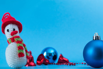 Knitted snowman on a blue background with bells and banks. Christmas cards.