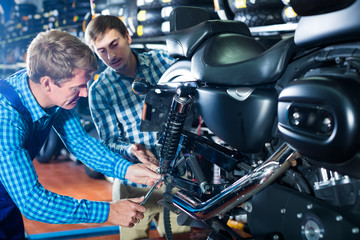 Young interested man customer asking technician about motorcycle