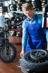 Mature man standing with motorcycle wheel