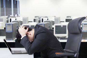 Depressed businessman with laptop on desk