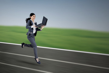 Female worker with laptop running on track