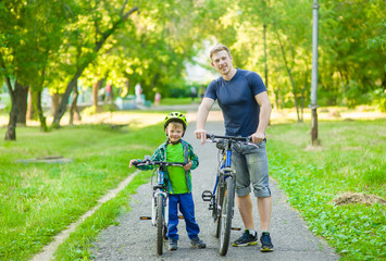 Obraz premium portrait of a happy family - father and son bicycling in the park