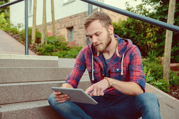 young man sitting on stairs and using tablet PC
