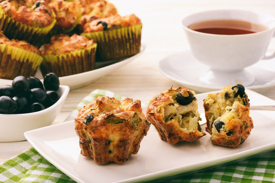 Appetizer - muffins with chicken, cheese and olives on white wooden background.