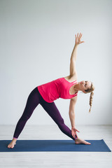 Naklejka premium Young woman in a white room doing yoga exercises .