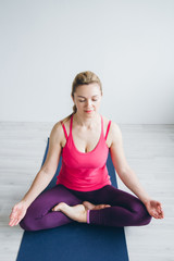 Fototapeta premium Young woman in a white room doing yoga exercises .