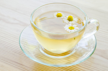 Cup of medicinal chamomile tea on the wooden table