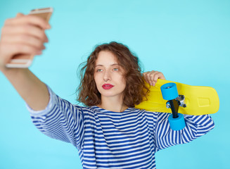 Hipster girl with skateboard making selfie