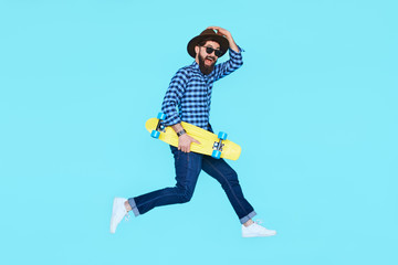 Pretty young bearded man jumping with yellow skateboard © kegfire