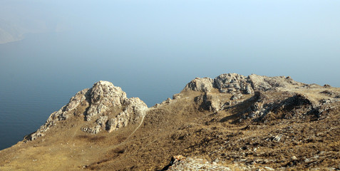 mountain landscape, volcanic rocks in the foreground. against the blue autumn sky in a haze. view from the extreme heights of Lake Baikal in the valley.photo toned