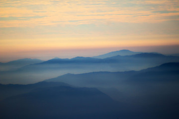Fototapeta na wymiar blue profiles of mountains in a misty sunset