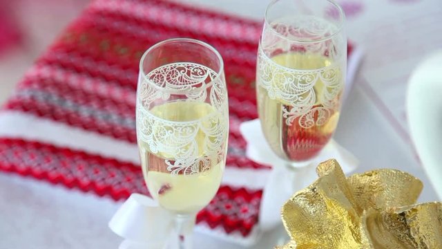 Close up of two wedding glasses full of champagne on festive table ready for bride and groom. Real time full hd video footage.