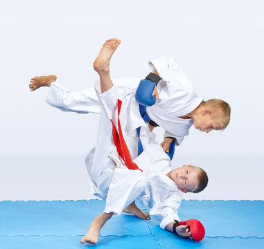 With blue and red overlays on hands boys are training judo throws