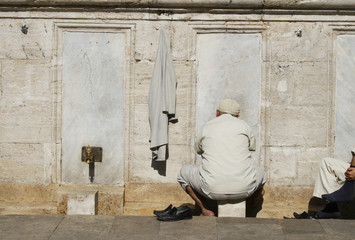 arab man washing feet near mosque