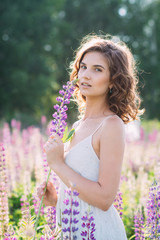 Girl with a bouquet of lupine on the field