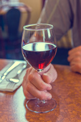 Holdihg a glass of red wine