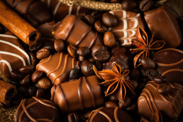 Assortment of white, dark, and milk chocolate. Chocolate with cream, nuts, almonds, hazelnuts and cinnamon with coffee beans. Sweet food and no diet concept.