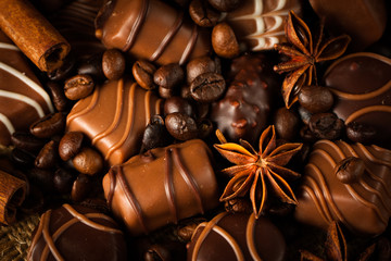 Assortment of white, dark, and milk chocolate. Chocolate with cream, nuts, almonds, hazelnuts and cinnamon with coffee beans. Sweet food and no diet concept.
