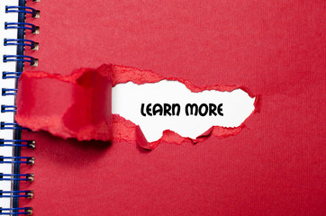 The word learn more appearing behind torn paper