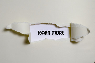 The word learn more appearing behind torn paper