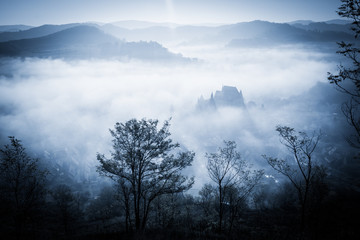 Mysterious misty morning over Biertan village, Transylvania, Romania. Blue colors. Halloween postcard concept.