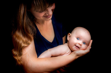 Newborn baby lying on the mother's hands isolated on black