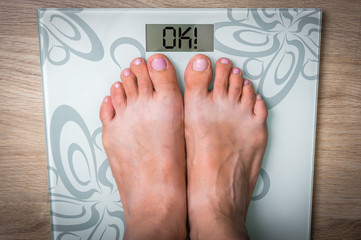 Woman's feet on a scale with word OK!