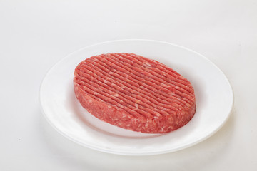 raw beef patties on a plate isolated