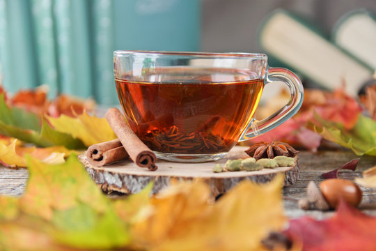 tea cup, books and autumn leaves on a wooden background