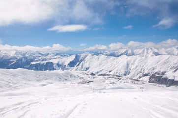 Fototapeta na wymiar Bird view on the ski village in valley. Background of snowboard resort from the high peak. Winter season for advertising or billboard