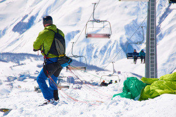 Ski paragliding prepairing for fly. Extreme sport in high mountains on snowboard resort. Happy, sport and health life.