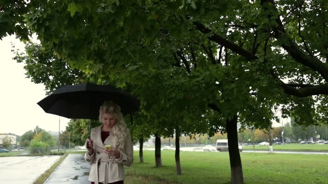 Blonde with umbrella and phone in hand