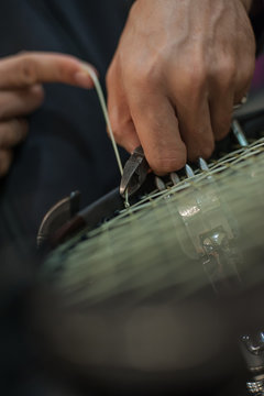 Stringing tennis racket. Tennis stringer tying knots and cutting string with pliers