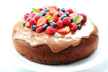 Homemade chocolate cake with berries on white wooden table