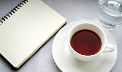 Obraz na płótnie Canvas Tea in white cup with Journal book