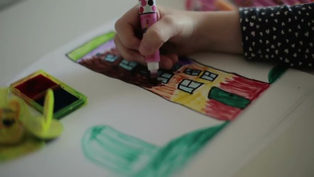 A child's hand drawing a house with a felt-tip pen. Slow motion.