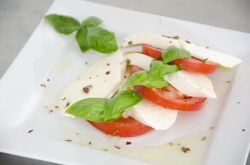 Detail of salad with tomatoes, basil and mozzarella on the table of stainless steel
