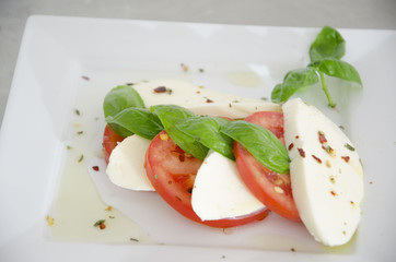 Detail of salad with tomatoes, basil and mozzarella on the table of stainless steel