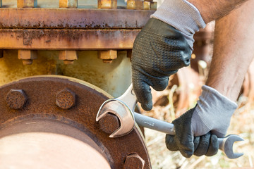 Hands with Work Gloves Holding a Wrench and Tighten very Rusty Bolts