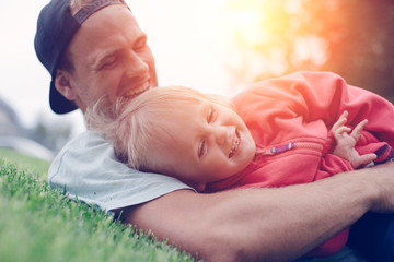 Happy father playing with daughter in the park at sunny day, intentional sun glare
