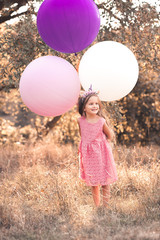 Smiling kid girl 5-6 year old playing with big balloons outdoors. Looking away. Childhood.